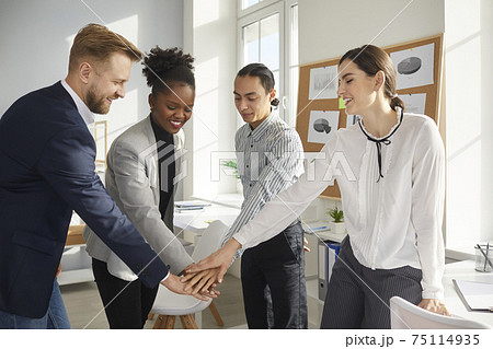 Multiracial colleagues fold their hands on each other as a symbol of cooperation and support. Multiracial colleagues fold their hands on each other as a symbol of cooperation and support. 75114935