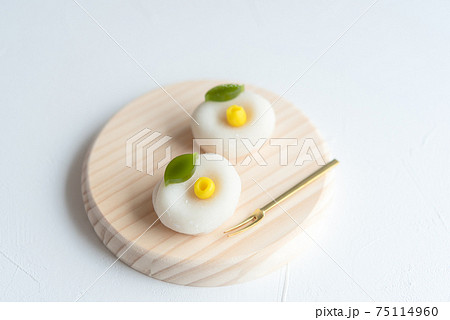 丸い木の皿に乗った上生菓子 白椿 和菓子 雪平 白い椿の花 の写真素材