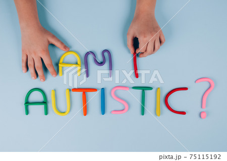 World Autism Awareness Day concept, symptoms - multicolored letters, Am I Autistic - on light blue background with child hand. Autism spectrum disorder and child mental health concept. Selective focus 75115192