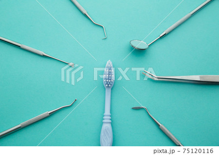 Dentist tools. Professional steel dental instruments with a mirror on light blue background. Dental health and teethcare concept. 75120116