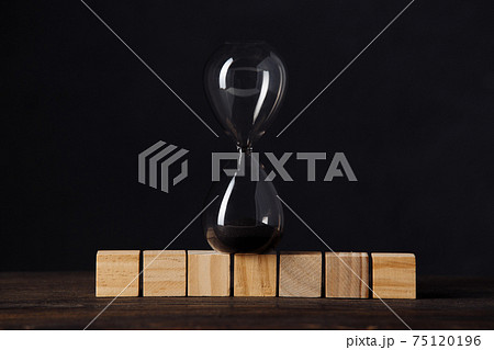 Hourglass or sandglass on cube wooden blocks, place for text, on wooden table with dark background 75120196