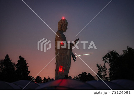 満月が昇る前に手からビームを放つ牛久大仏の写真素材
