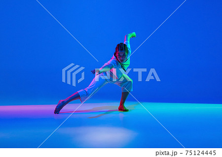 Young girl dancing hip-hop in white attire on colorful background in neon light 75124445