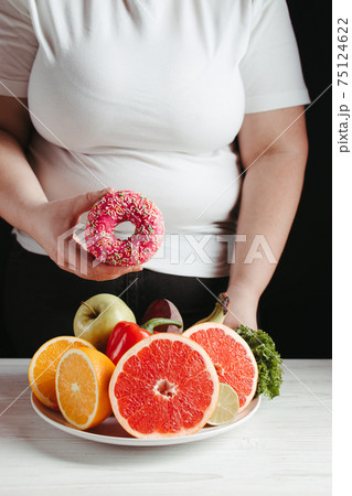 Fat woman choosing between healthy and junk food Fat woman choosing between healthy and junk food 75124622