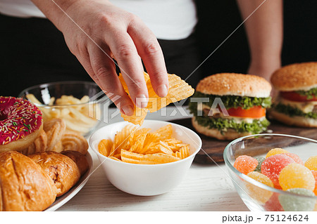 Woman eating unhealthy food, compulsive overeating 75124624