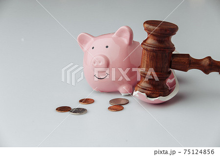 Broken pink piggy bank with coins and wooden judge gavel on a white background. Auction or bankruptcy concept 75124856