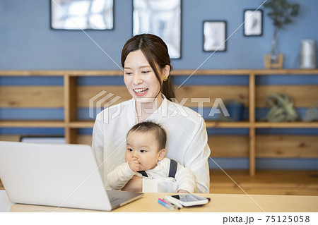 赤ちゃんを抱えてノートパソコンを操作する女性 75125058