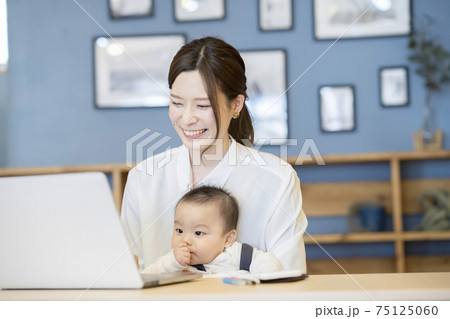 赤ちゃんを抱えてノートパソコンを操作する女性 75125060