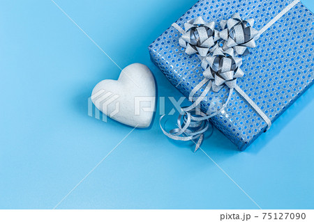 Gift box Packed in blue paper on a blue background . Gift box Packed in blue paper on a blue background . 75127090