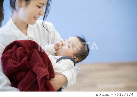 寝ている赤ちゃんを抱っこするお母さん 寝ている赤ちゃんを抱っこするお母さん 75127274