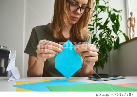DIY concept. Woman make origami easter rabbit from color paper. Origami lessons DIY concept. Woman make origami easter rabbit from color paper. Origami lessons 75127587
