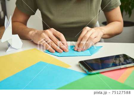 DIY concept. Woman make origami easter rabbit from color paper. Origami lessons 75127588