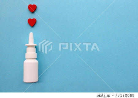 Two red hearts and a bottle of nasal spray on a blue background. Healthcare. Vasoconstrictors. Two red hearts and a bottle of nasal spray on a blue background. Healthcare. Vasoconstrictors. 75130089