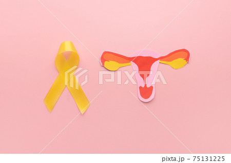 Yellow ribbon awareness with uterus shape made frome paper on pink background. Symbol of  National Endometriosis awareness month of March. Female reproductive health concept. 75131225