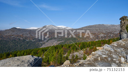Autumn mountain landscape .Hill slope with coniferous thickets against the background of mountain ranges and blue sky. Autumn mountain landscape .Hill slope with coniferous thickets against the background of mountain ranges and blue sky. 75132153