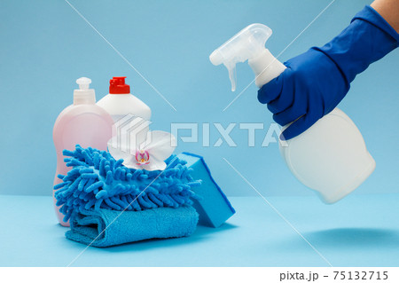 Woman's hand in a protective glove with a bottle of glass and tile cleaner on the blue background. 75132715