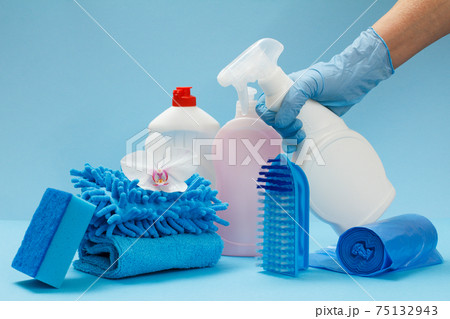 Woman's hand in protective glove with bottle of glass and tile cleaner on the blue background. 75132943