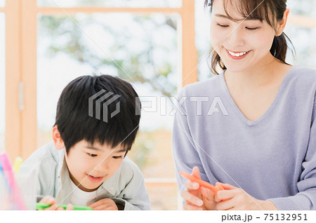 子供に文字の書き方を教える母親 75132951