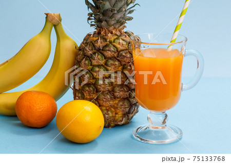 Fresh tropical fruits and a glass of juice on a blue background. Fresh tropical fruits and a glass of juice on a blue background. 75133768