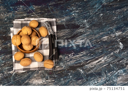 Walnut kernels on a dark table, a whole walnut in a wooden bowl. selective focus 75134751