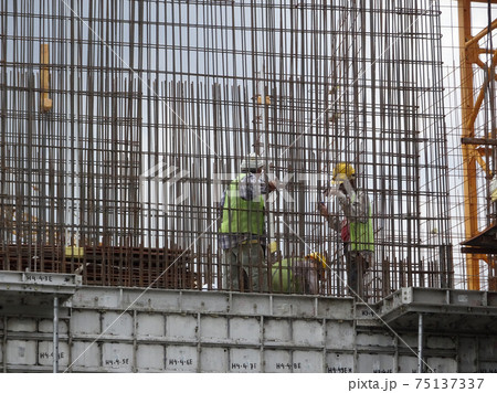 KUALA LUMPUR, MALAYSIA -AUGUST 26, 2017: Construction workers fabricating vertical steel reinforcement bar at the construction site.  75137337