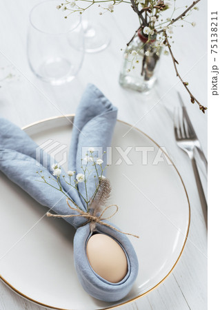 Easter table setting with egg in blue Easter Bunny napkin. Easter table setting with egg in blue Easter Bunny napkin. 75138211