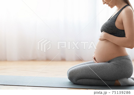 Prenatal Yoga. Smiling Pregnant Woman Sitting On Fitness Mat And Touching Belly Prenatal Yoga. Smiling Pregnant Woman Sitting On Fitness Mat And Touching Belly 75139286