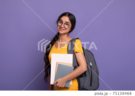Happy indian female student wearing eyeglasses holding notebooks Happy indian female student wearing eyeglasses holding notebooks 75139468