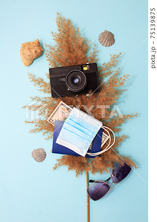 Travel concept with hat, camera, mask, passport and glasses on blue background. Flat lay composition Travel concept with hat, camera, mask, passport and glasses on blue background. Flat lay composition 75139875