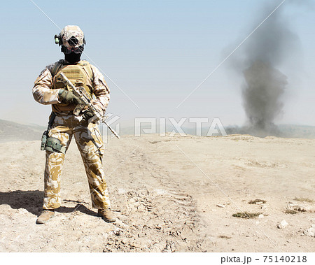 Photo of a fully equipped military soldier standing with automatic rifle of war desert background. 75140218