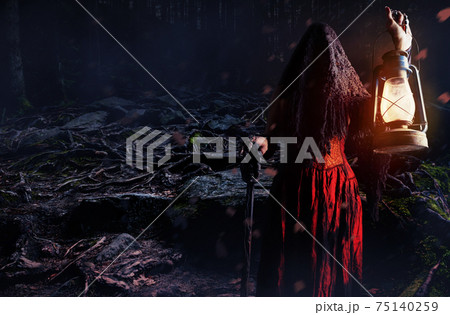Wide angle photo of a female witch holding lantern and cane in dark woods. 75140259