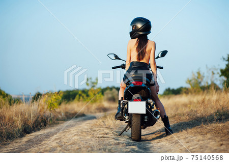 girl biker without underwear in a helmet sitting on a black motorcycle 75140568