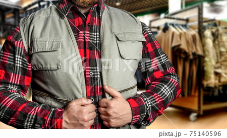 Photo of a bearded man in uniform store putting on hunting jacket. Photo of a bearded man in uniform store putting on hunting jacket. 75140596
