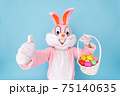 Happy easter. Easter bunny or rabbit or hare holds egg with basket of colored eggs, having fun, celebrates Easter rabbit isolated on blue background 75140635