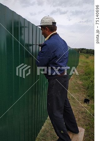 Fastening of a metal sheet to a framework of a fence by means of the screw-driver, screwing of screw-drivers in a fence. 75140696