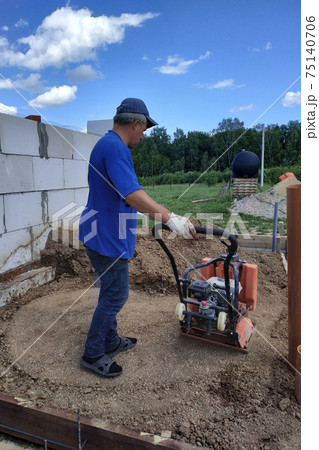 Construction work on the construction site, soil compaction with a vibrating plate, manual equipment. Construction work on the construction site, soil compaction with a vibrating plate, manual equipment. 75140706