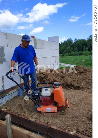 Construction work on the construction site, soil compaction with a vibrating plate, manual equipment. Construction work on the construction site, soil compaction with a vibrating plate, manual equipment. 75140707