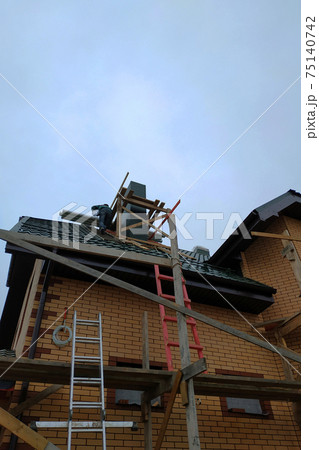Construction and insulation of a new house with facade bricks, construction work and wooden scaffolding. Construction and insulation of a new house with facade bricks, construction work and wooden scaffolding. 75140742