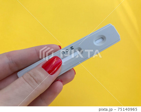 medical procedures. coronavirus test on a bright yellow background. girl with bright red manicure holds a strip. IgG and IgM antibodies test 75140965