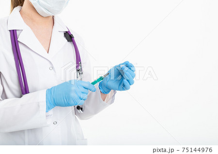 A young nurse in a mask opens a syringe on a white background in a white coat, to make a vaccination 75144976