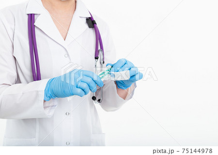 A young nurse in a mask opens a syringe on a white background in a white coat, to make a vaccination 75144978