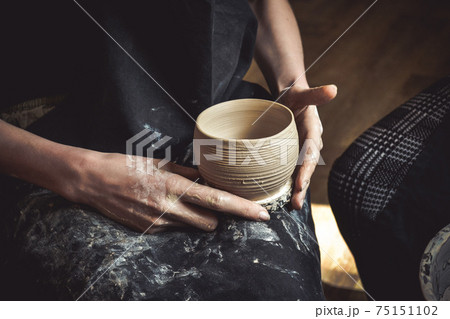 A raw clay pot in the hands of a potter A raw clay pot in the hands of a potter 75151102
