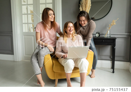 a group of girlfriends communicate with a friend via a video conference on a laptop. Friendship 75155437
