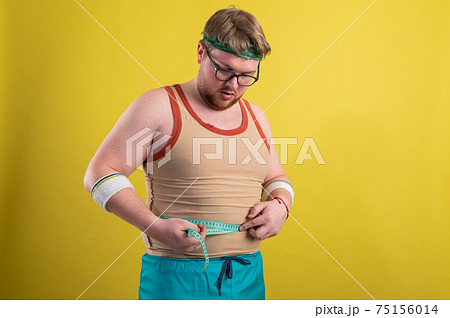 a man in sportswear measures his body volume. Healthy lifestyle concept, healthy food 75156014