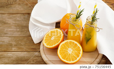 Orange juice in glass bottles. The juice is decorated with a sprig of rosemary Orange juice in glass bottles. The juice is decorated with a sprig of rosemary 75156445