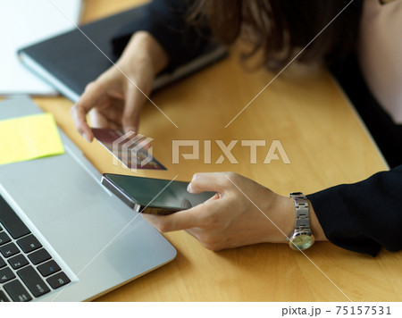 Cropped shot of businesswoman online paying with smartphone and debit card Cropped shot of businesswoman online paying with smartphone and debit card 75157531