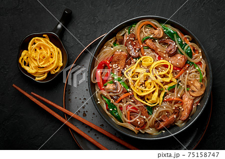 Japchae in black bowl on dark slate table top. Korean cuisine food glass chapchae noodles dish Japchae in black bowl on dark slate table top. Korean cuisine food glass chapchae noodles dish 75158747