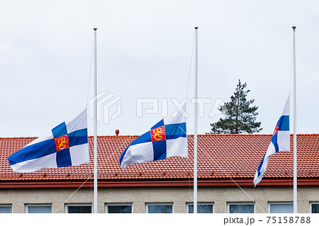 Three finnish flags lowered to half mast on the occasion of mourning at cloudy autumn day Three finnish flags lowered to half mast on the occasion of mourning at cloudy autumn day 75158788