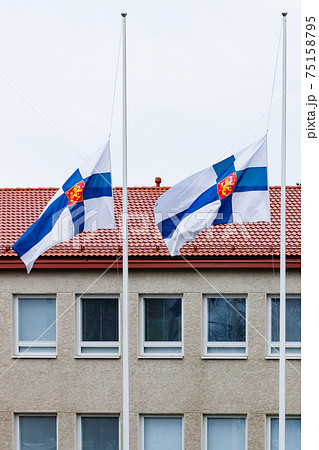 Three finnish flags lowered to half mast on the occasion of mourning at cloudy autumn day Three finnish flags lowered to half mast on the occasion of mourning at cloudy autumn day 75158795
