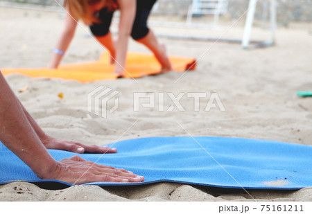 Yoga on the beach. Close-up of girls legs in lotus position. Blurred background for signature. Doing sports, Pilates, stretching outdoors 75161211
